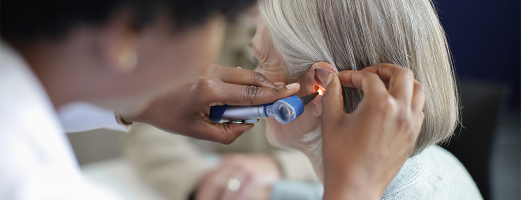 Image of female hearing care professional shining a light inside the ear of a senior female patient
